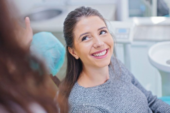 woman sits in dental chair listening to dentist Asheville North Carolina