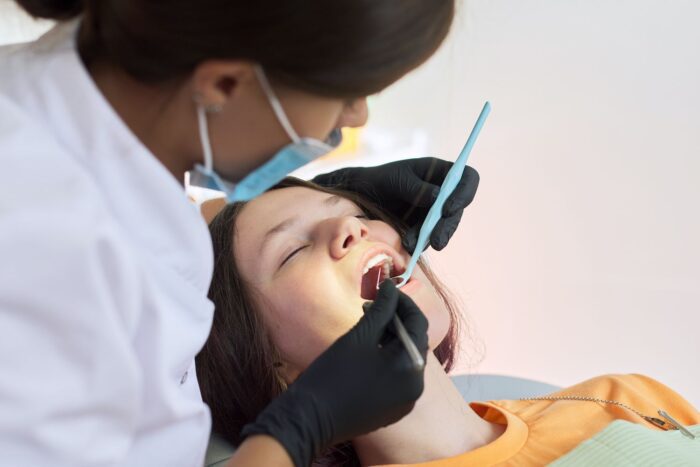 Woman dentist treating teeth to a patient sitting in dental chair using professional equipment general dentistry dentist in Asheville North Carolina
