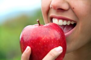 Young woman biting into an apple teeth whitening cosmetic dentistry dentist in Asheville North Carolina